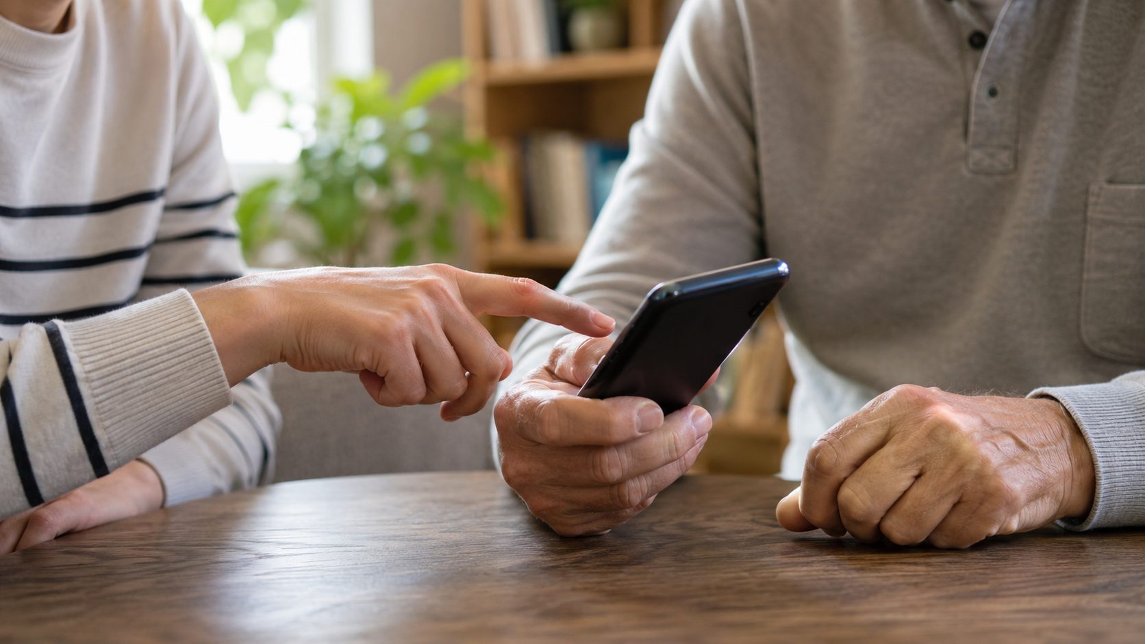 Yaşlı bir kullanıcıya telefonundaki sahte SMS mesajını gösteren genç el