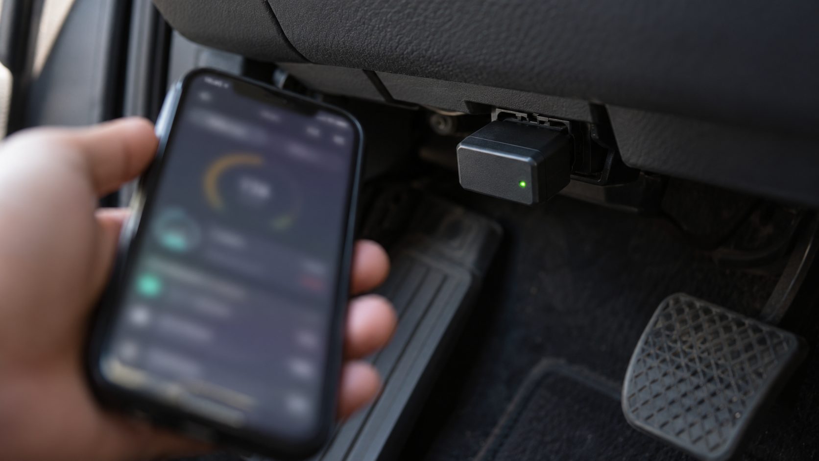Bluetooth OBD2 adapter plugged into a car's diagnostic port with a smartphone ready to pair in its app